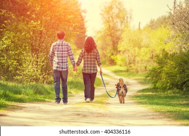 Young happy couple with dog on the leash walking in village back to camera - Powered by Shutterstock