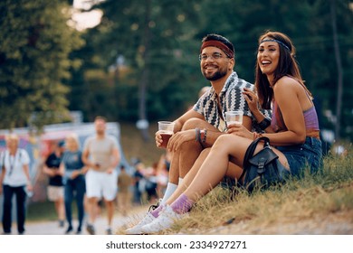 Young happy couple drinking beer while sitting on grass during open air music festival.  - Powered by Shutterstock