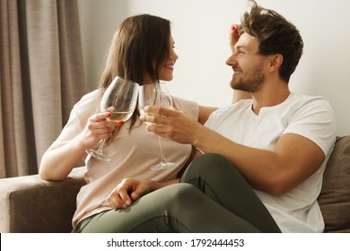 Young And Happy Couple Drinking Wine And Relaxing At Home