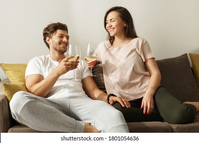 Young And Happy Couple Drinking Wine And Relaxing At Home