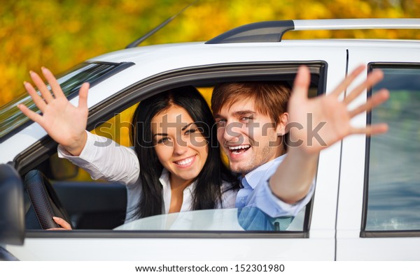 young happy couple\
driving in car. excited couple on road trip in new car. holding\
hands up open palm at you