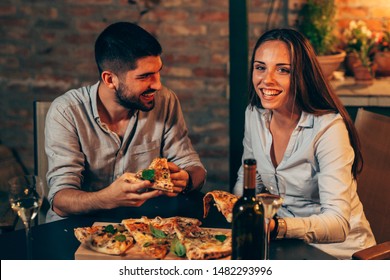 Young Happy Couple Eating Pizza And Drinking Wine At Home In Backyard. Night Scene.