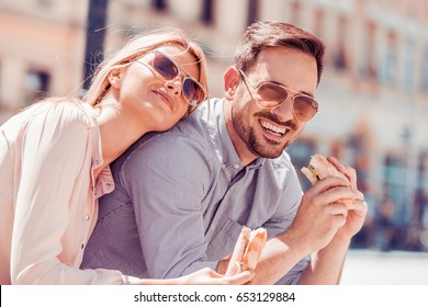 Young Happy Couple Eating Sandwich Together In The City,having A Date.