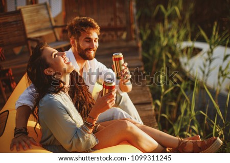 Young happy couple enjoy in beer by the river during the sunset