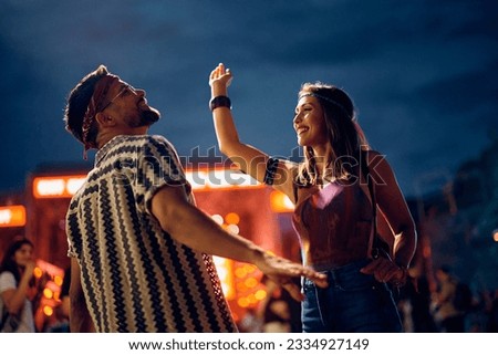 Young happy couple enjoying in dancing during open air  music festival at night.
