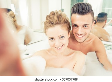 Young happy couple enjoying jot bath in the jacuzzi. taking a selfie in the jacuzzi