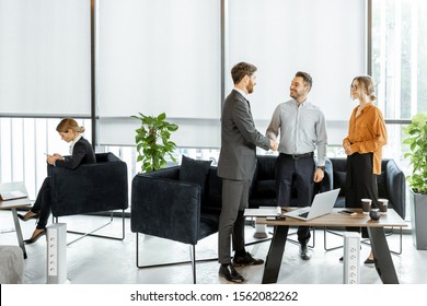 Young And Happy Couple Having A Deal, Shaking Hands With Financial Consultant Or Real Estate Agent At The Luxury Office