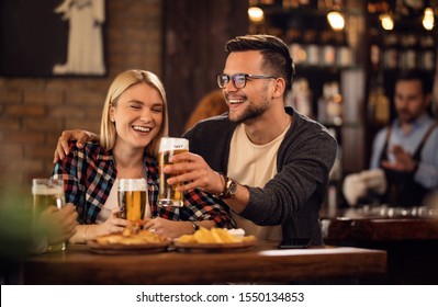 Young happy couple having fun together while toasting with beer in a bar,  - Powered by Shutterstock