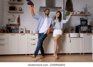 Young happy couple having fun while doing cleaning kitchen, They hold the rags with spray bottle in hands and happily to dancing, smile and laugh together, Happy family concept - Powered by Shutterstock