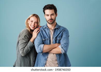 Junge, glückliche Paare, die sich umarmen und lächeln, während sie sich auf der Kamera einzeln auf blauem Hintergrund