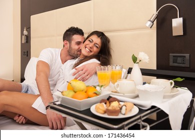 Young Happy Couple Joking While Having Breakfast In Luxury Hotel Room.