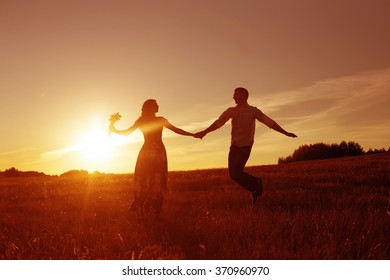 Young happy couple jumping on sunset