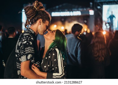 Young Happy Couple Kissing At Music Festival In The Night. Young People In Love. Love, Music And Celebration Concept.