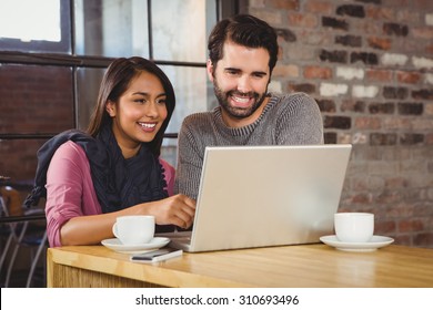 Young Happy Couple Looking At A Laptop In The Cafe