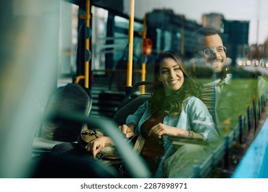 Young happy couple looking through the window while riding in a bus. Copy space.