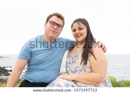 young happy couple in love embracing while dating on seaside on summer day, man and woman smiling with eyes closed while enjoying intimate moment outdoors