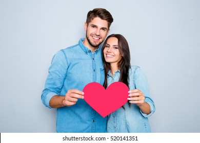 Young Happy Couple In Love Holding Red Paper Heart.