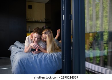 Young Happy Couple In Love Lying In Bed In Morning In Their New Home In Tiny House,sustainable Living Concept.