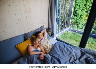 Young Happy Couple In Love Lying In Bed In Morning In Their New Home In Tiny House,sustainable Living Concept.