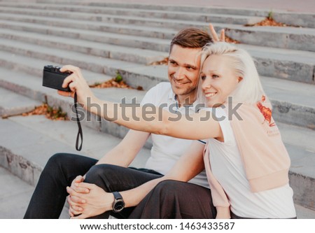 Young happy couple in love making selfie on retro camera on the city street