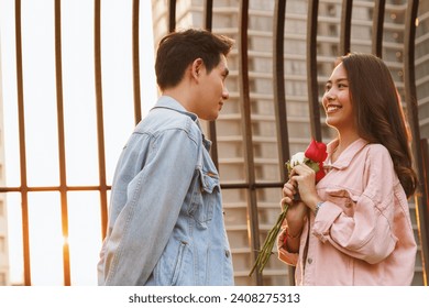 young happy couple love and romantic at first date relationship. asian teenage woman surprise and smiling at boyfriend gives red rose flowers at dinner in valentine day. couple and happiness concept. - Powered by Shutterstock