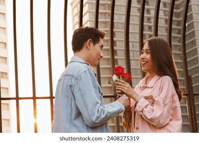 young happy couple love and romantic at first date relationship. asian teenage woman surprise and smiling at boyfriend gives red rose flowers at dinner in valentine day. couple and happiness concept. - Powered by Shutterstock