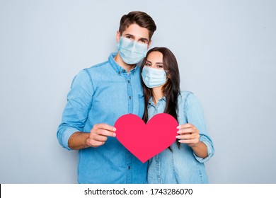 Young Happy Couple In Love Story Photo Shoot Holding Red Paper Heart Wear Medical Safety Sterile Mask On Face, Social Distance Pandemic Corona Virus Prevention Protection Concept Covid 19