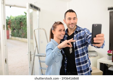 Young happy couple moving in new house and calling friends and family with cellphone in their brand new apartment