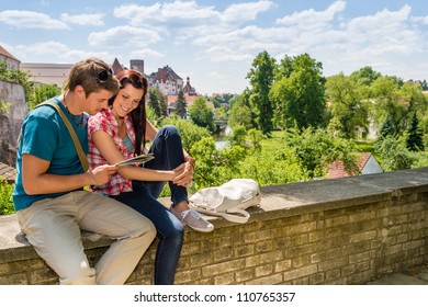 Young Happy Couple On Vacation In City Looking At Map