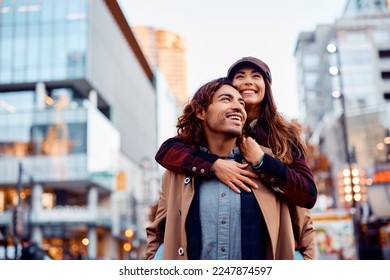 Young happy couple piggybacking and having fun together in the city.