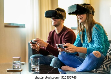 Young Happy Couple Playing Video Games Virtual Reality Glasses In Their Apartment - Cheerful People Having Fun With New Trends Technology - Gaming Concept - Focus On Woman Headset