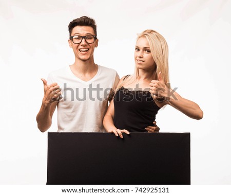 Young happy couple portrait of a confident businessman showing presentation, pointing placard gray background. Ideal for banners, presentation, landings, presenting concept.