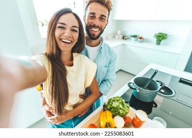 Young happy couple preparing healthy meal in kitchen at home - Husband and wife cooking salad - Food and healthy lifestyle concept - Powered by Shutterstock