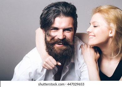 Young Happy Couple Of Pretty Woman With Blonde Hair And Handsome Bearded Man With Long Beard Embracing And Smiling On Grey Background