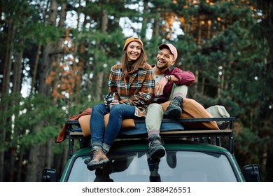 Young happy couple relaxing on a roof of their camper van in nature. Copy space.  - Powered by Shutterstock