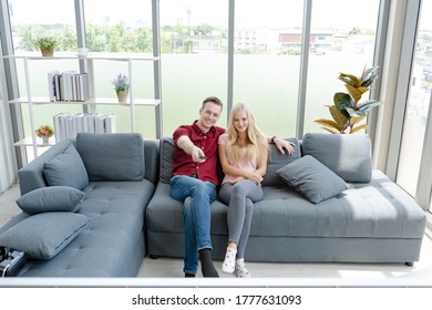 Young happy couple relaxing and smiling. Free time together. Happy beautiful couple is spending weekend together on couch indoors at home. - Shutterstock ID 1777631093