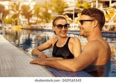 young happy couple relaxing together in tropical resort swimming pool. summer vacation, romantic getaway - Powered by Shutterstock