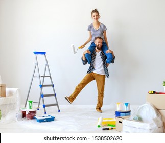 young happy couple is repairing and painting the wall at home