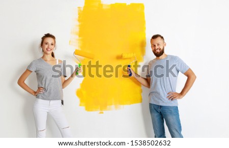 young happy couple is repairing and painting the wall at home
