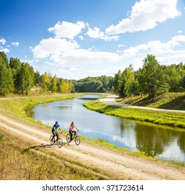 Young Happy Couple Riding Bicycles by the River - Powered by Shutterstock