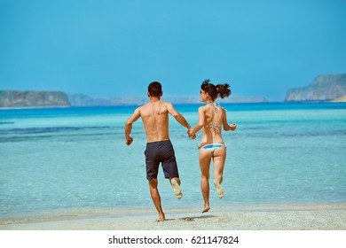 Young Happy Couple Running On The Beach. Balos Beach, Crete, Greece.