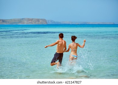 Young Happy Couple Running On The Beach. Balos Beach, Crete, Greece.