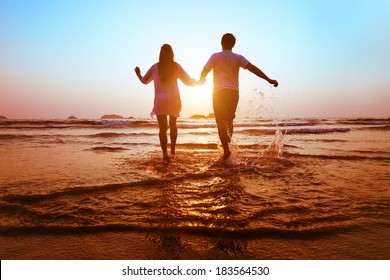 young happy couple running to the sea at sunset beach - Powered by Shutterstock