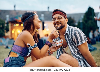 Young happy couple sharing mini donuts at open air music festival. - Powered by Shutterstock