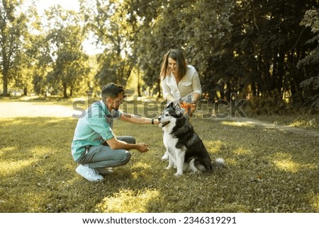 Young happy couple with siberian husky dog in the summer park.
