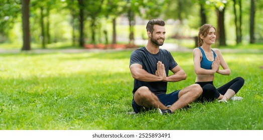 Young happy couple  sitting in lotus position or woman practicing with man, bearded coach trainer, doing yoga exercises meditating, after outdoor training. Wide panoramic banner concept image. - Powered by Shutterstock