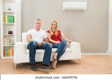 Young Happy Couple Sitting On White Sofa 