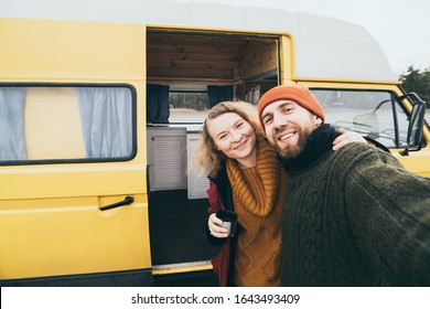 Young happy couple taking selfie in front of their yellow self-converted off-grid camper van - Powered by Shutterstock