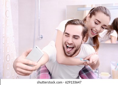 Young Happy Couple Taking Selfie While Brushing Teeth In Bathroom