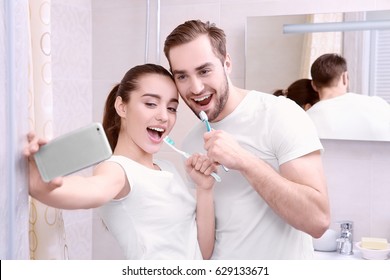 Young happy couple taking selfie while brushing teeth in bathroom - Powered by Shutterstock